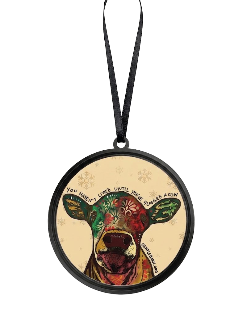 Round Christmas ornament featuring a colorful illustrated cow with a black hanging ribbon, shown on a plain white background.